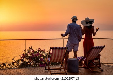 A loving couple on vacation time enjoys the beautiful summer sunset over the mediterranean sea with a glass of wine - Powered by Shutterstock