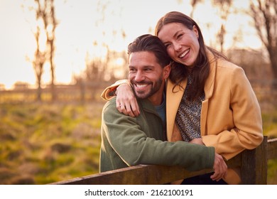 Loving Couple On Walk Through Autumn Countryside Resting On Fence Together - Powered by Shutterstock