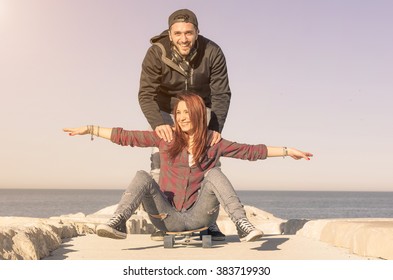 Loving couple playing on the skateboard outdoor - sport, love, and people concept - caucasian people - Powered by Shutterstock