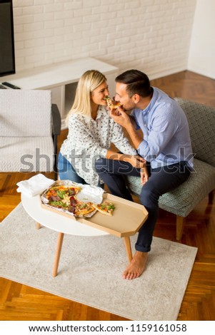 Loving couple relaxing at home and eating tasteful pizza