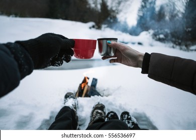 Loving couple resting and drinking  coffee together in snow outdoor. Winter holidays in mountains.