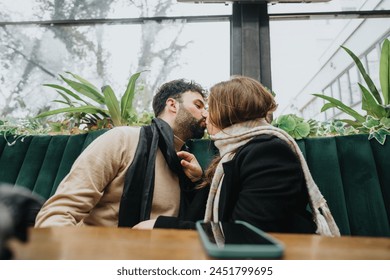 A loving couple shares a kiss at a city cafe among green plants, capturing a romantic moment in an urban outdoor setting. - Powered by Shutterstock