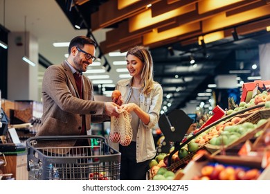 Loving couple shopping some groceries together in supermarket. They put fruit in a bag - Powered by Shutterstock