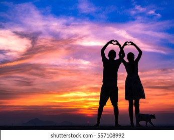 Loving couple showing heart symbol on hands,twilight background