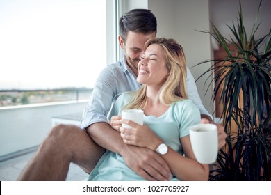 Loving Couple Sit Next To The Window.They Drink Coffee.