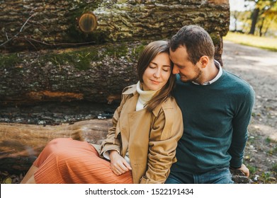 Loving couple sitting on the felled logs in the forest. Man and woman embracing. love story. Closeup - Powered by Shutterstock