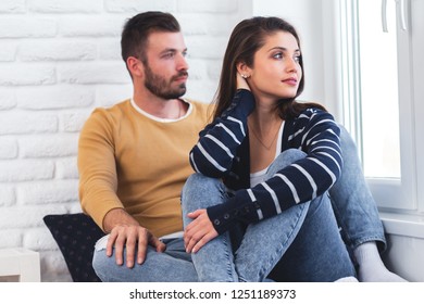 Loving couple sitting together by the window and relaxing in apartment. - Shutterstock ID 1251189373