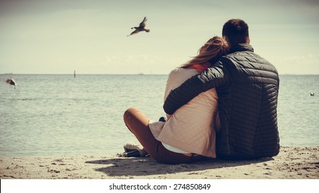 loving couple spending leisure time together at beach hugging rear view