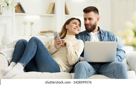 Loving Couple Spending Time Together, Woman Showing Phone To Husband, Man Using Laptop