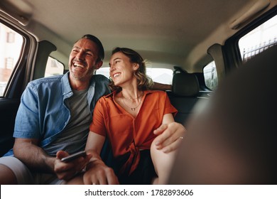 Loving Couple Travelling In The Backseat Of A Cab. Smiling Man And Woman Going Out In A Taxi.