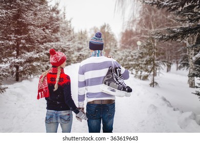 Loving couple walking on a date in a winter Park. On the back of a guy hangs a pair of skates.