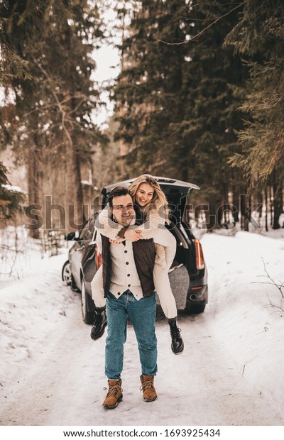 Loving couple are walking in the winter\
in the forest near the car, NOISE EFFECT ON\
PHOTOS