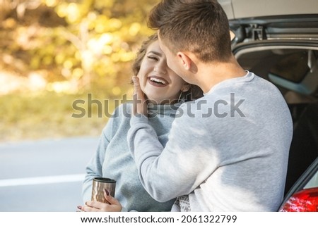 A loving couple walks in the autumn forest. Hot tea in a thermo mug. Happy laugh. Concept for love, happy family, travel and weekend.