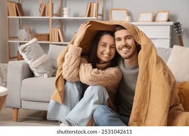 Loving couple with warm plaid sitting at home on winter day - Powered by Shutterstock