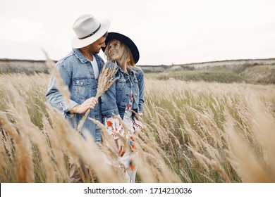 Loving couple in a wheat field. Beautiful blonde in a blue hat. - Powered by Shutterstock