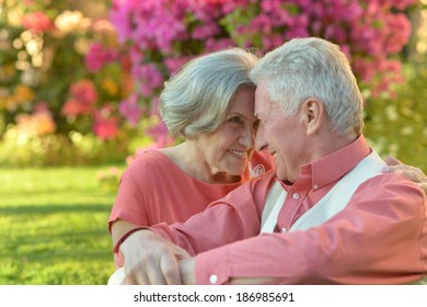 Loving elder couple sitting on a background of flowers - Powered by Shutterstock