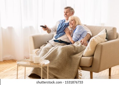 Loving Elder Couple Watching Tv At Cold Winter Day, Covered With Blanket