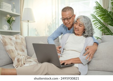 Loving elderly couple spending quality time together, using laptop in cozy living room. - Powered by Shutterstock