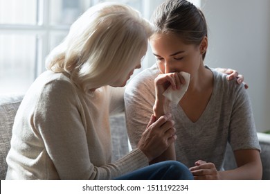 Loving elderly mother hug crying millennial daughter show support and care after relationships breakup, supportive senior 60 woman embrace cuddle grownup child feeling depressed, having life problems