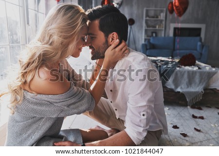 Photo of Loving everything about her. Beautiful young couple bonding and smiling while sitting in the bedroom