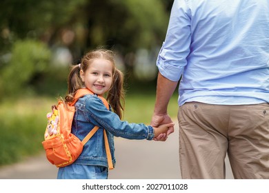 Loving Family. A Caring Dad Accompanies A Little Girl With Backpacks To School. The Child Smiles And Looks Over His Shoulder. Close-up. Back To School. The First Day Of Training