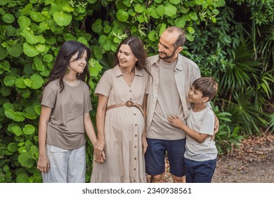 A loving family enjoying a leisurely walk in the park - a radiant pregnant woman after 40, embraced by her husband, and accompanied by their adult teenage children, savoring precious moments together - Shutterstock ID 2340938561