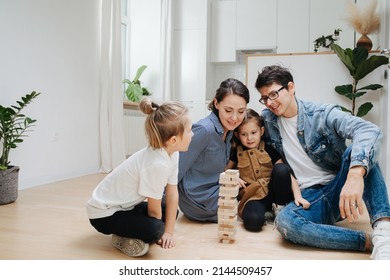 Loving family playing jenga on the floor, pulling out tiles. Parents hugging little girl, boy sitting opposite of them. - Powered by Shutterstock