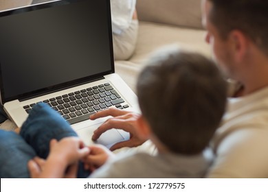 Loving father and son using laptop on sofa in house