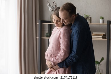 Loving future parents expecting their first baby hugging standing at home, caring husband touch belly of pregnant wife feel love, express caress to unborn child. Cherish, parenthood, new life concept - Shutterstock ID 2174173119