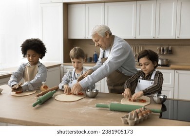 Loving great-grandpa teach to cook his little great-grandchildren, using shape cutters prepare home-made bakery enjoy process and communication at home. Share experience with younger gen, family ties - Powered by Shutterstock