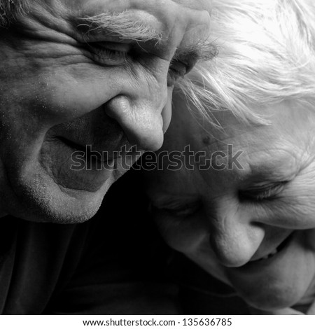 A loving, handsome senior couple on a black background.