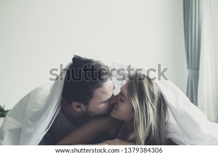 Happy young couple in love kissing under duvet cover