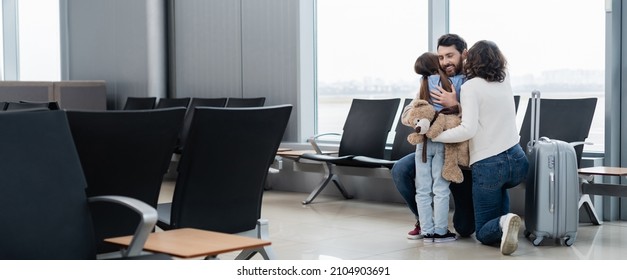 Loving And Happy Family Hugging In Airport Lounge, Banner