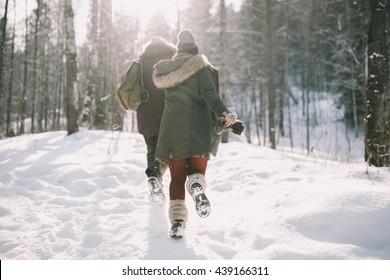 A Loving Happy Young Couple Emotionally Runs In The Winter Woods. View Back