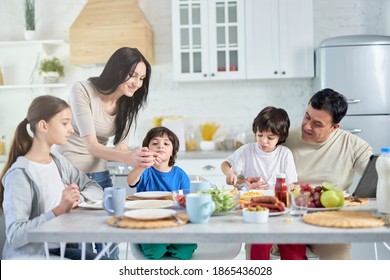 Loving hispanic parents taking care of their little children, entertaining them while having lunch together at home - Powered by Shutterstock