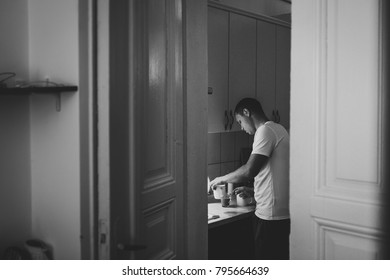 Loving husband is preparing a coffee in kitchen for his wife, side view through door. The Valentine's Day Concept. Celebrating holiday. Lifestyle. Black and white photo. Women's Day, eighth of March. - Powered by Shutterstock