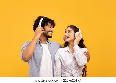Loving indian couple in headphones listening to music, hugging and looking at each other over yellow studio background. Excited lady enjoying favorite sountracks with her boyfriend - Shutterstock ID 2107625177