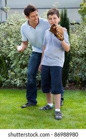 Loving Little Boy Playing Baseball With His Father In Their Backyard