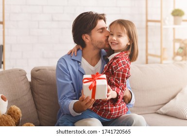 Loving little daughter giving her dad present, father kissing little girl, Father Day concept, home interior, free space - Powered by Shutterstock