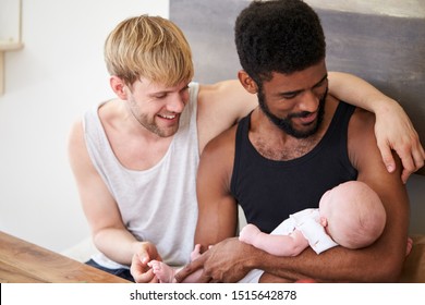 Loving Male Same Sex Couple Cuddling Baby Daughter At Home Together