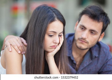 Loving man comforting upset offended friend hugging her from behind, showing support. Couple in fight concept - Powered by Shutterstock