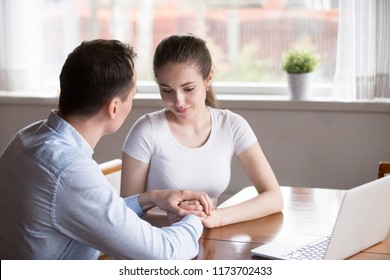 Loving man holding woman hands looking at her showing love and understanding, millennial couple reconciled after fight caressing and enjoying time together, male comfort female expressing support