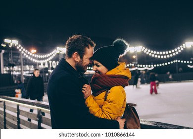 Loving man and woman on the skating rink smiling at each other with their eyes closed