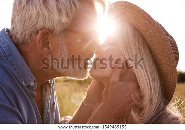 Loving Mature Couple In Countryside About To Kiss\
Against Flaring Sun