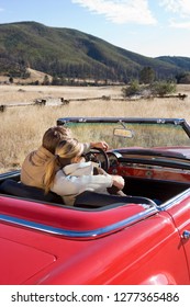 Loving Mature Couple Driving Classic Red Convertible Car On Road Trip