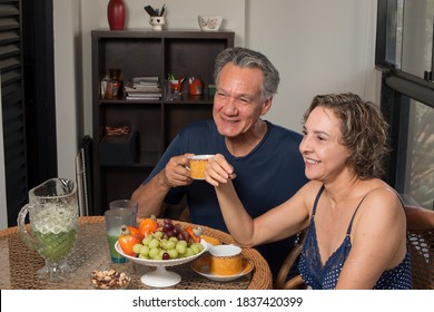 Loving Mature Couple Enjoying A Lite Breakfast In There Sunroom

