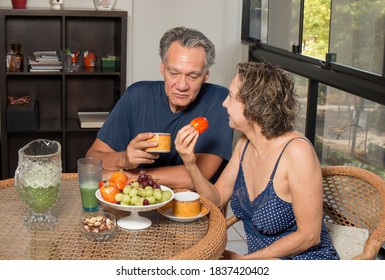 Loving Mature Couple Enjoying A Lite Breakfast In There Sunroom

