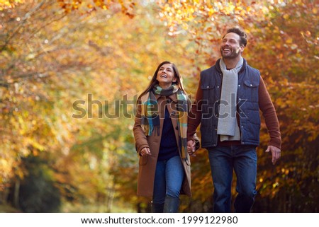 Loving Mature Couple Holding Hands Walking Along Track In Autumn Countryside