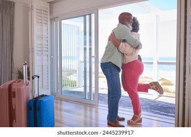 Loving Mature Couple With Luggage Arriving In Beachfront House Overlooking Ocean For Summer Vacation - Powered by Shutterstock