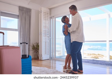 Loving Mature Couple With Luggage Arriving In Beachfront House Overlooking Ocean For Summer Vacation - Powered by Shutterstock